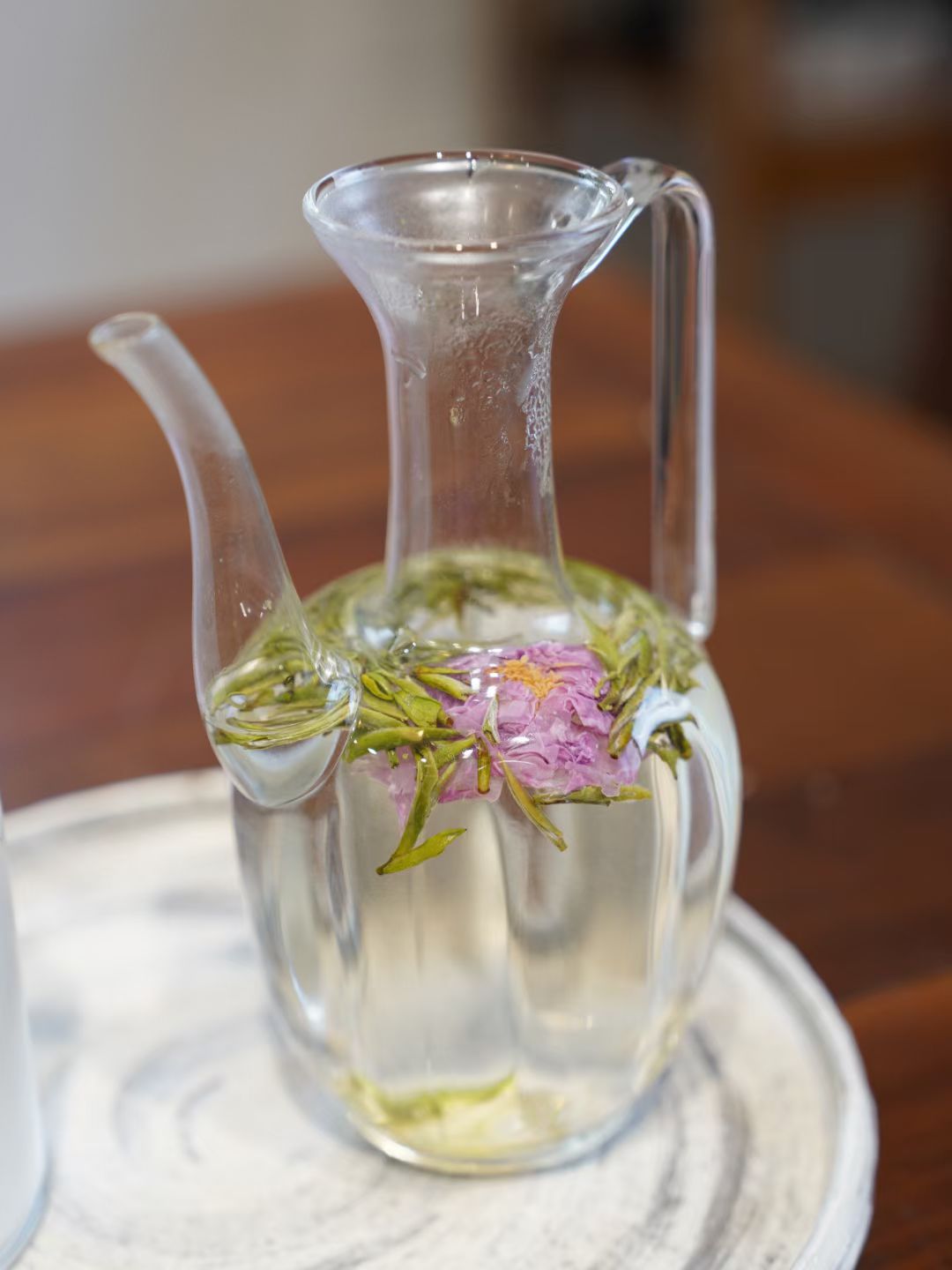 Clear glass pitcher with floral elements on a wooden surface