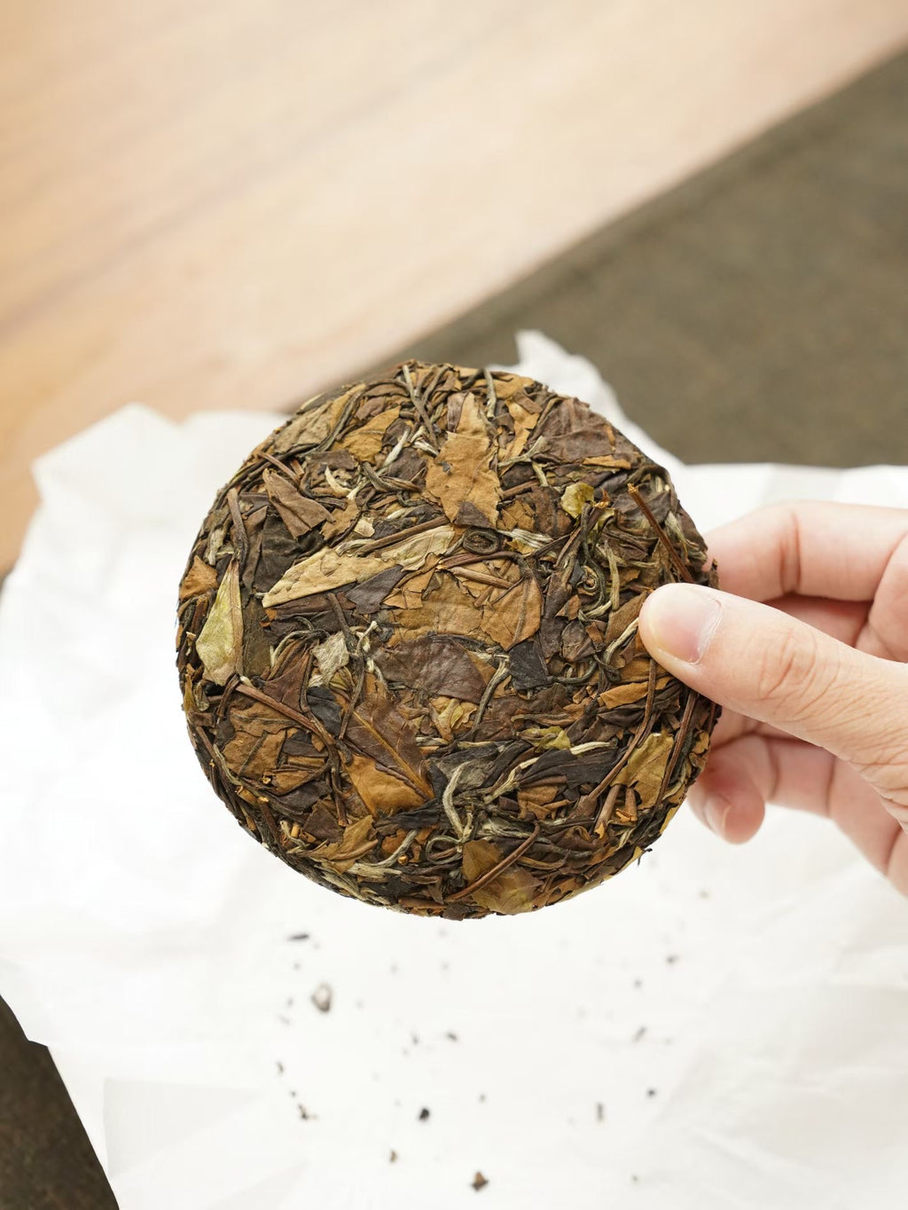 Hand holding a round, pressed tea cake with a blurred background
