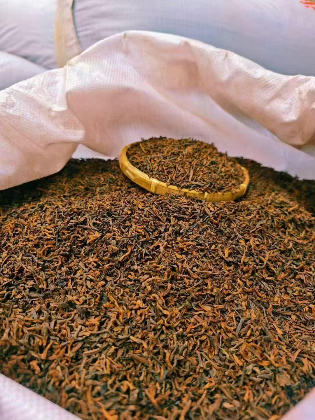 A close-up of loose-leaf tea leaves in a large white sack, with a small bamboo scoop holding a pile of the dark brown and golden-brown tea leaves. Ten years in the making. Ready in a minute.
Aged ripe pu-erh, loose and ready to brew. Two tins, one to open now, one to keep deepening.