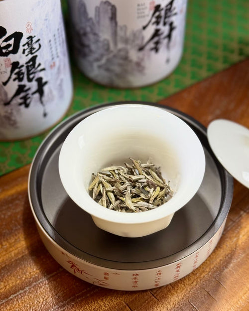 Aged Silver Needle white tea from 2020, six years matured. High-mountain single buds, honeyed aroma, warm medicinal notes, clear golden liquor. Four sealed tins — drink now or keep aging.