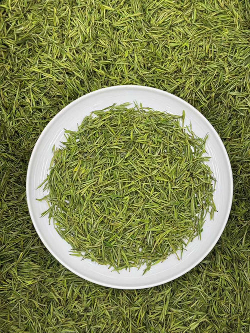 Green tea leaves on a white plate with a green background