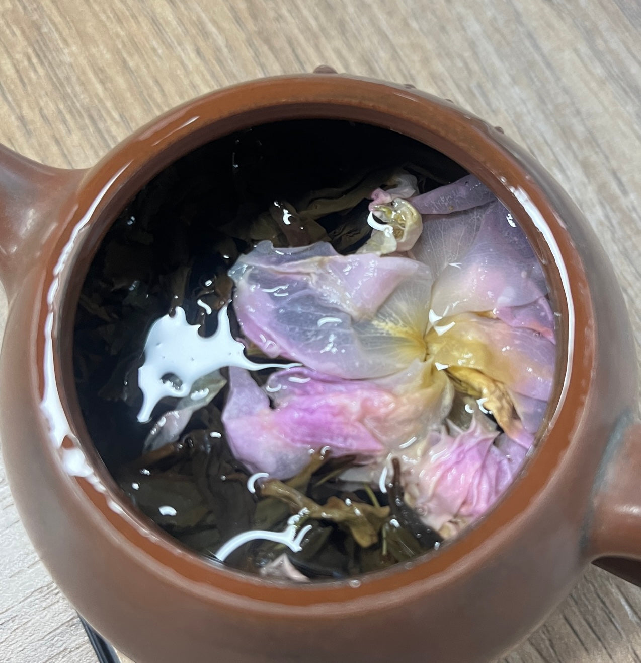Jinshan Rose Tea · Sichuan Plateau | Siguniang Mountain, 3000m Altitude. Ceramic teapot with flowers floating in the water on a wooden surface