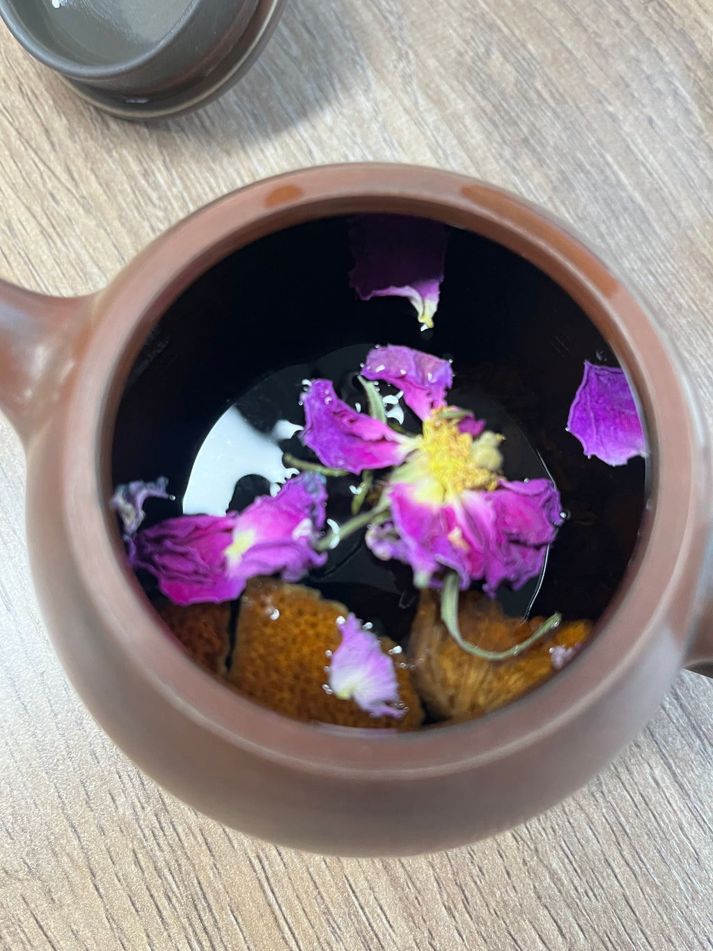 Jinshan Rose Tea · Sichuan Plateau | Siguniang Mountain, 3000m Altitude. Tea with purple flowers and tea leaves in a ceramic teapot on a wooden surface