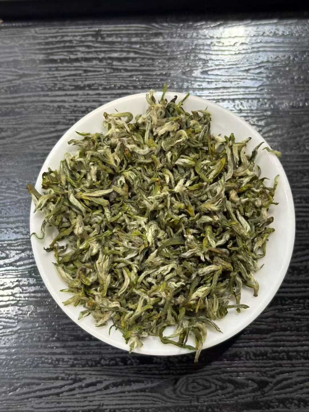 Mengding Ganlu · 2026 First Harvest | Ancient Mountain Green Tea from Sichuan Dry green tea leaves on a white plate with a dark wooden background