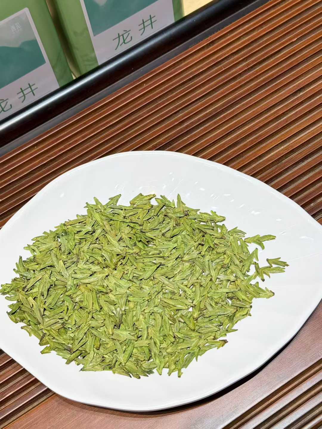 Longjing · 2026 Yu Qian Harvest | Pre-Rain Dragon Well Green Tea Green tea leaves on a white plate with a wooden surface