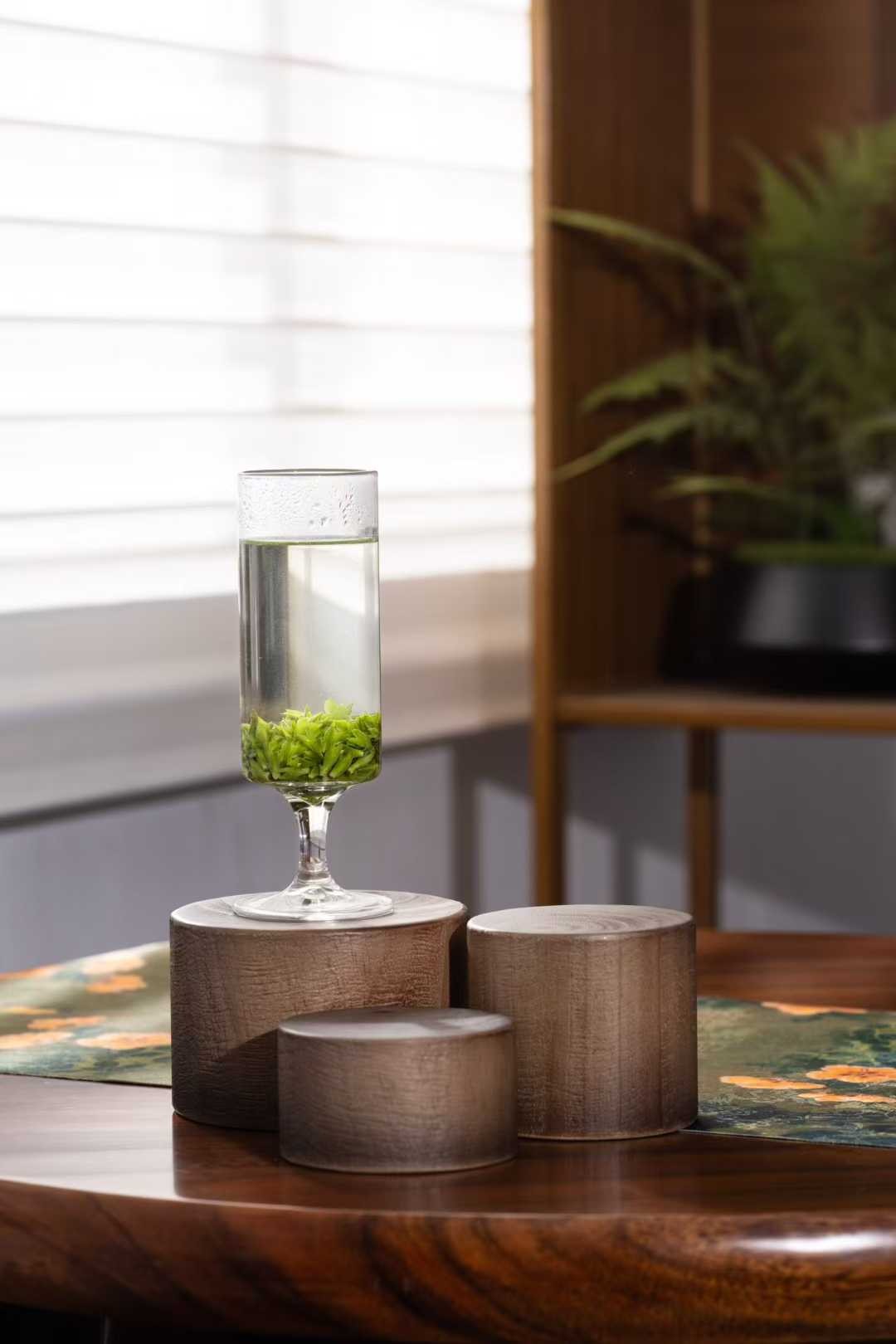 Small-Leaf Kuding · 2026 First Spring | Pure Rice-Bud Harvest, Glass vase with water and green leaves on a wooden surface with a blurred background