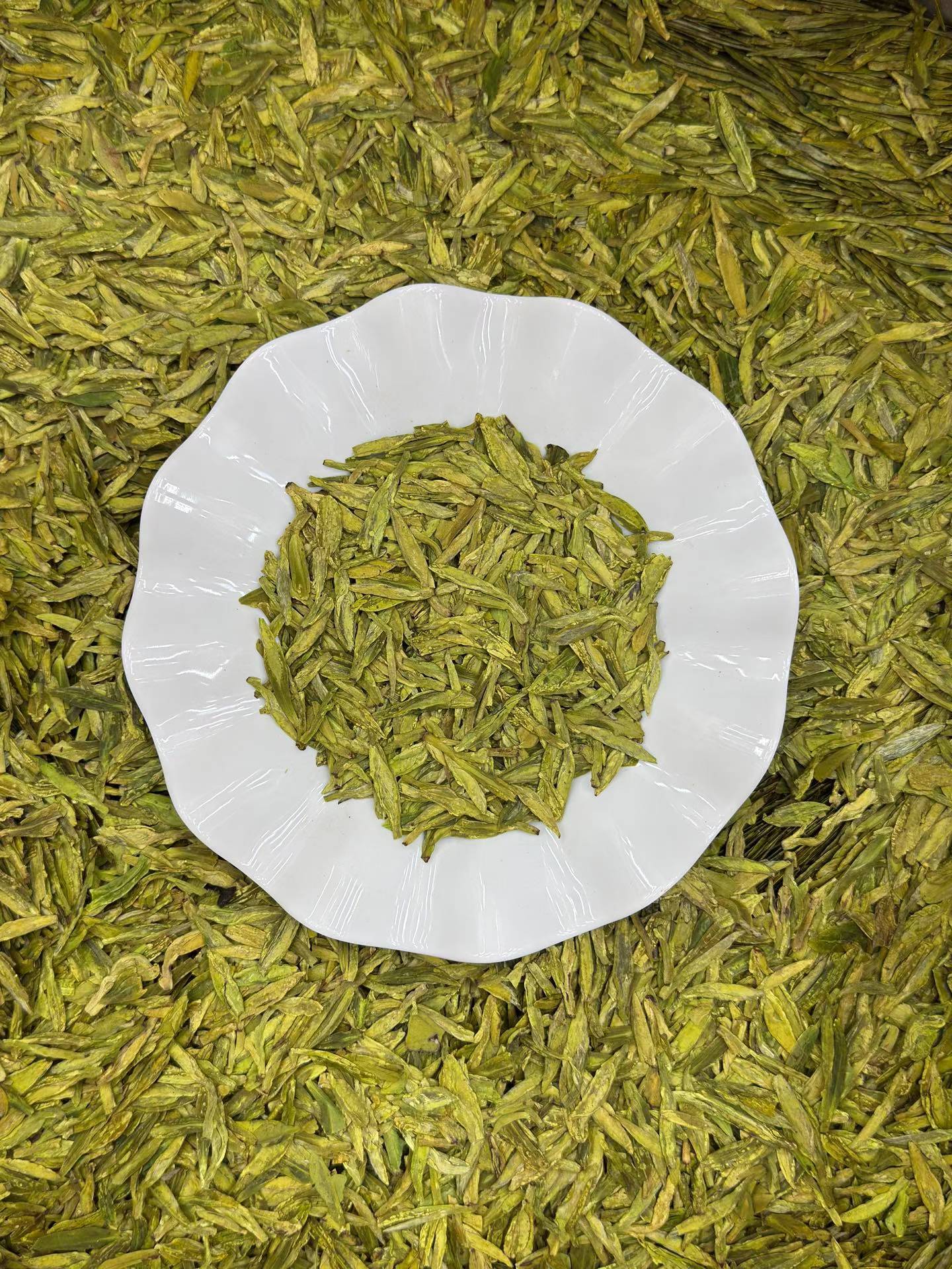 Green tea leaves on a white plate with more tea leaves in the background
West Lake Longjing 2026 pre-Qingming first flush. Calm focus, no jitter. Toasted chestnut fragrance, naturally sweet. Authentic West Lake origin. Spring limited.