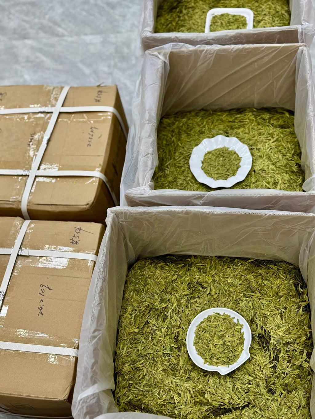 Boxes filled with green material and a cardboard box with white tape.