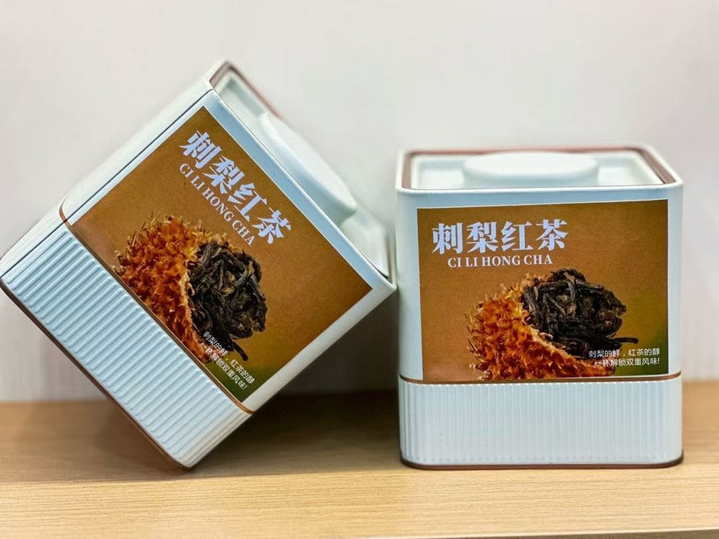 Two tea tins labeled 'Cili Hong Cha' on a wooden surface with a white background. Ci li black tea — aged tea leaves brewed inside whole wild rose hip fruit from Guizhou. Natural vitamin C, golden liquor, creamy finish. Nothing added.