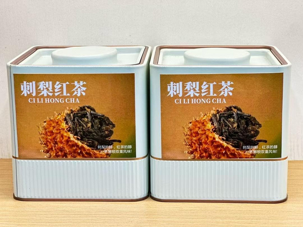 Two tins of CI LI HONG CHA tea on a wooden surface with a white background. Ci li black tea — aged tea leaves brewed inside whole wild rose hip fruit from Guizhou. Natural vitamin C, golden liquor, creamy finish. Nothing added.