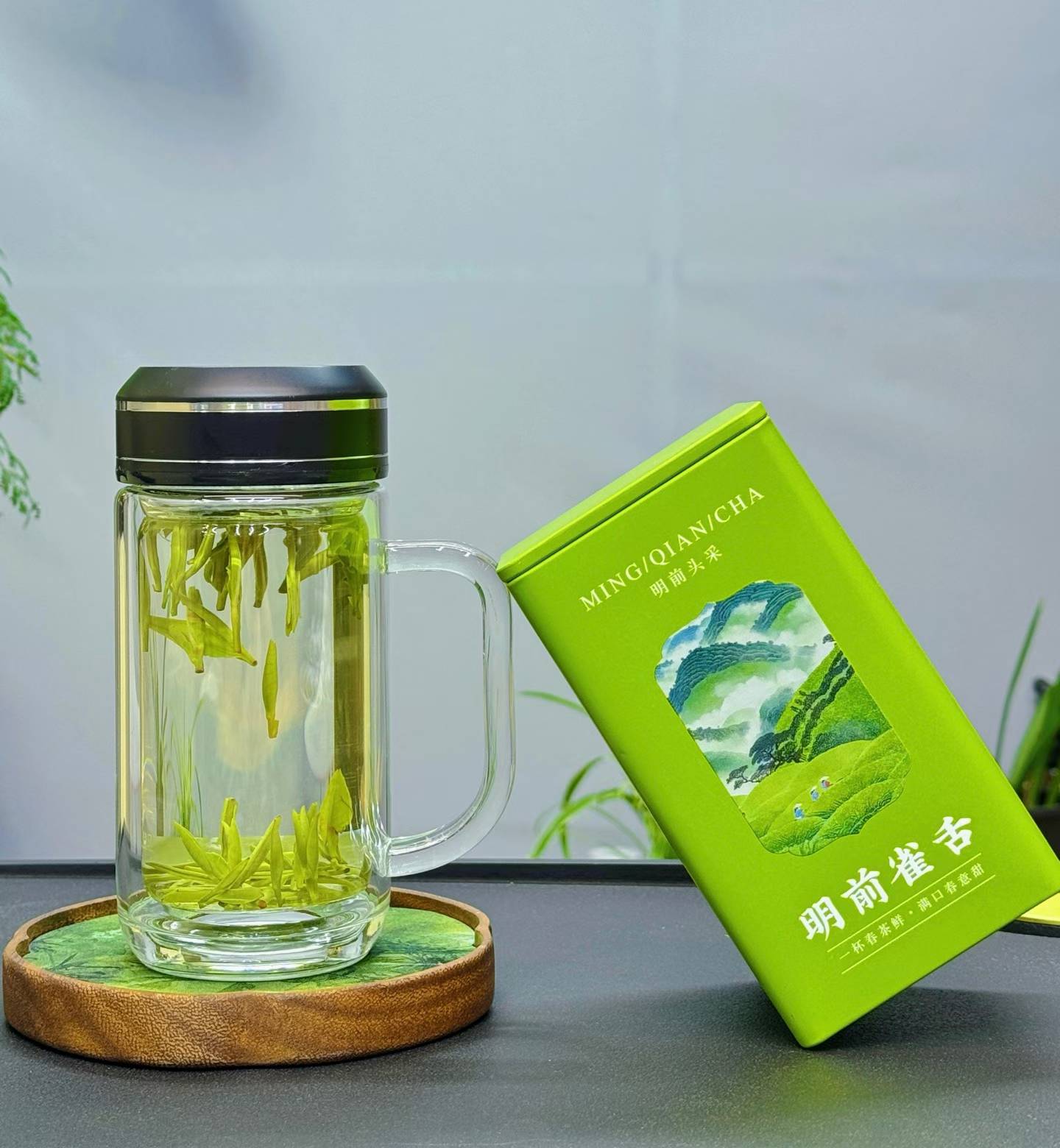 Clear glass mug with green tea leaves and a green tea box on a wooden coaster. Four of China’s most iconic spring green teas — harvested during the precious pre-Qingming season, when tea buds are at their most tender, fragrant, and vibrant.