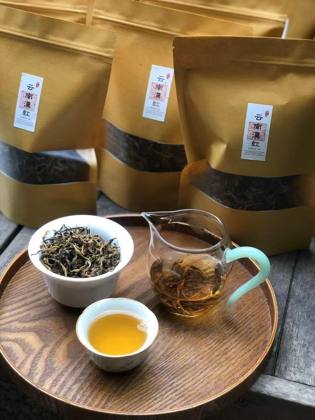 Tea leaves in a bowl, brewed tea in a glass cup, and tea packaging on a wooden tray. Yunnan nuoxiang black tea with a natural glutinous rice aroma. Mellow, warming, deeply comforting. A daily ritual tea for stress relief and quiet evenings.