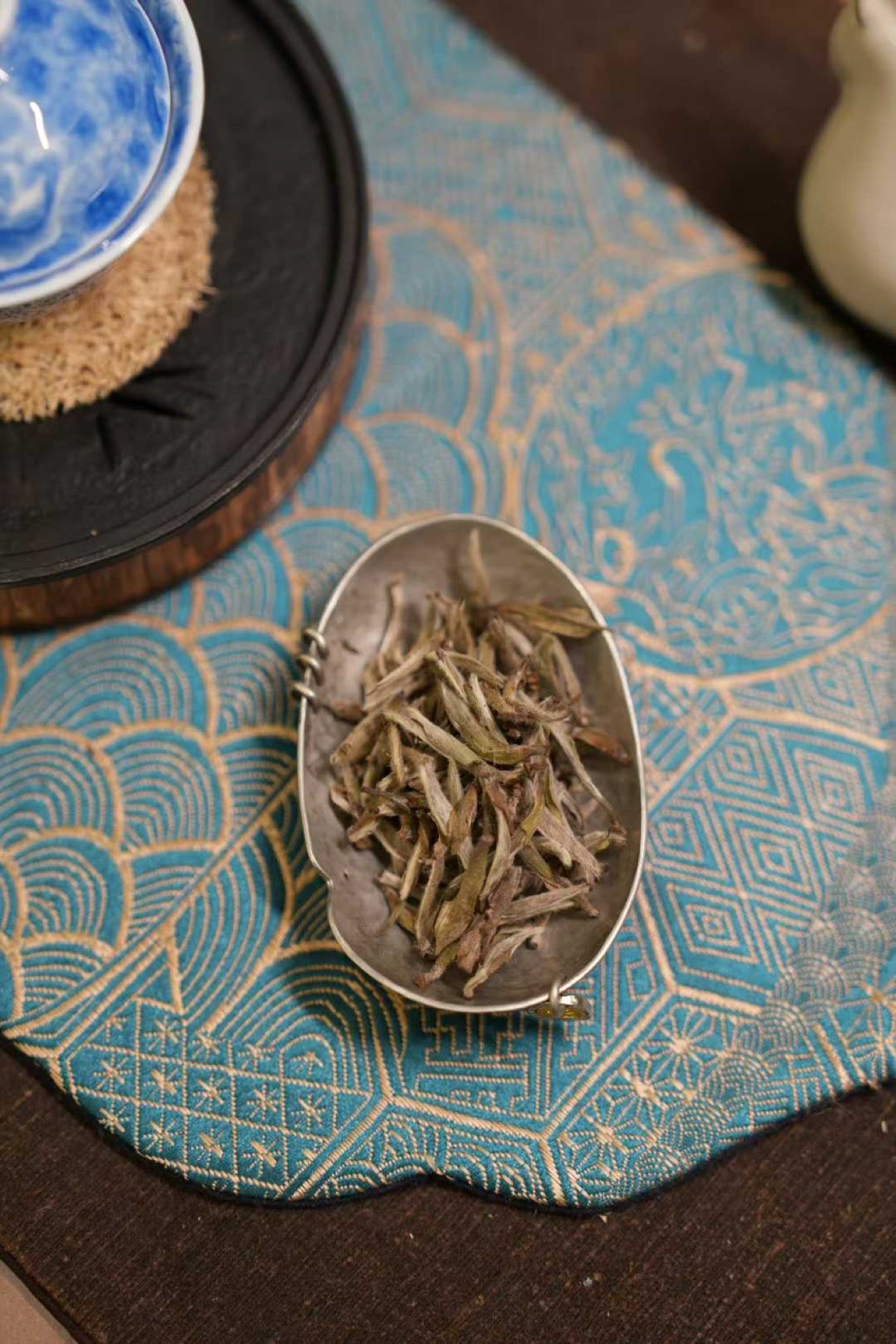 2017 Wild-Grown Silver Needle White Tea (Fuding)  Tea leaves in a silver spoon on a blue patterned mat