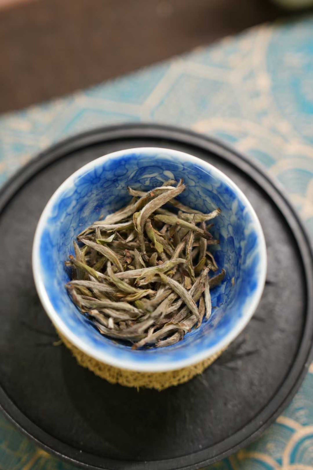 2017 Wild-Grown Silver Needle White Tea (Fuding)  Blue ceramic bowl with dried tea leaves on a textured surface