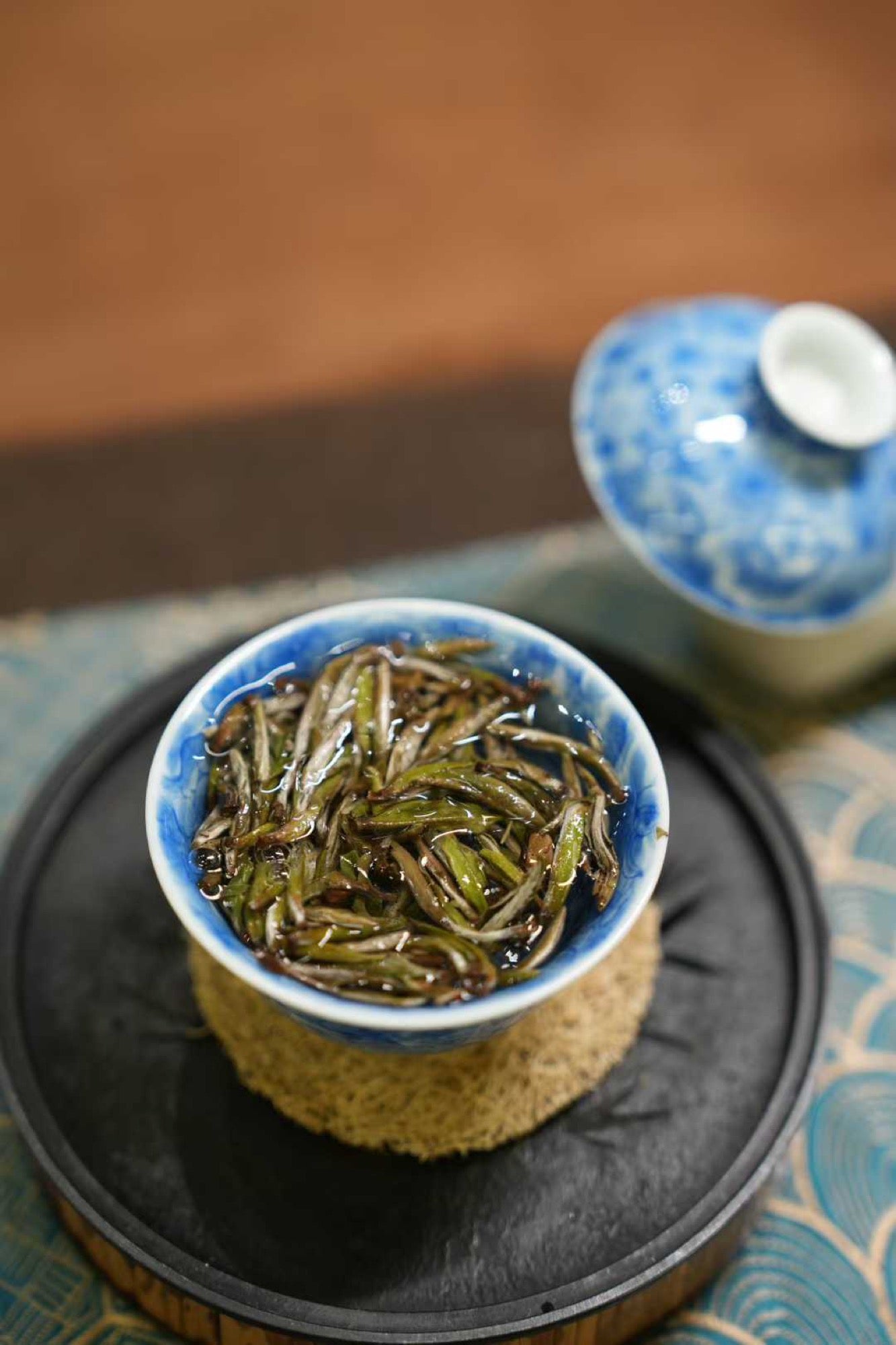 2017 Wild-Grown Silver Needle White Tea (Fuding)  Blue ceramic bowl with green tea leaves on a textured surface