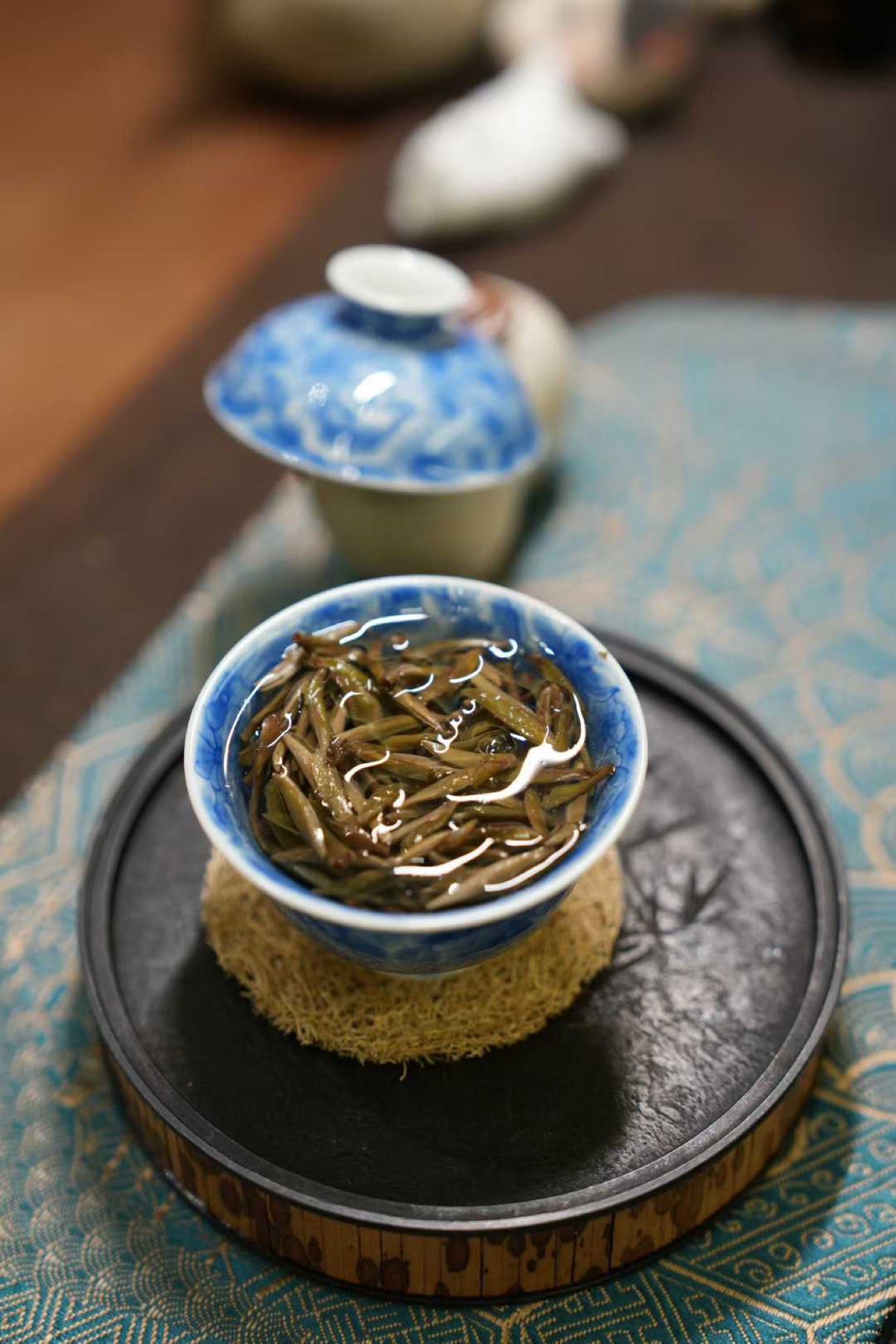 2017 Wild-Grown Silver Needle White Tea (Fuding)  Tea cup with green tea leaves on a textured surface