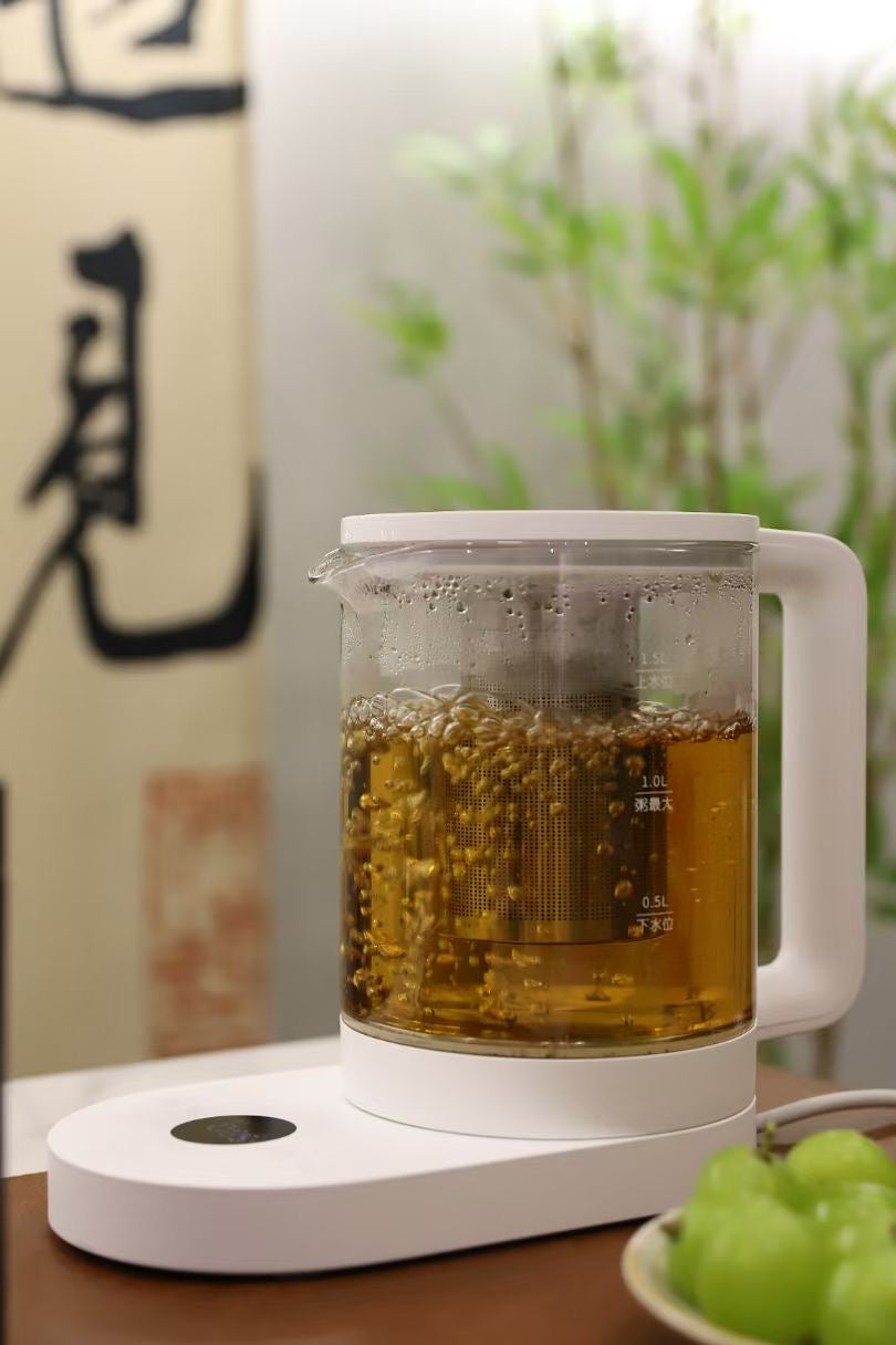Tea maker with hot tea on a wooden surface, with grapes and a blurred background
